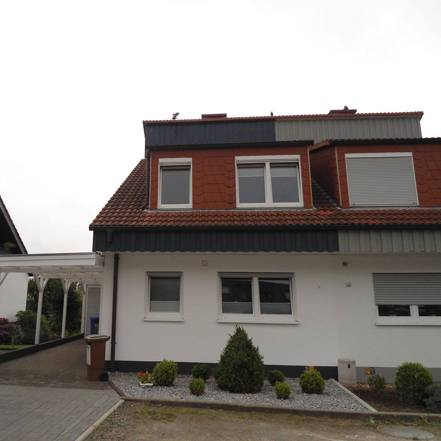 Zweifamilienhaus mit hellem Putz und roten Gauben