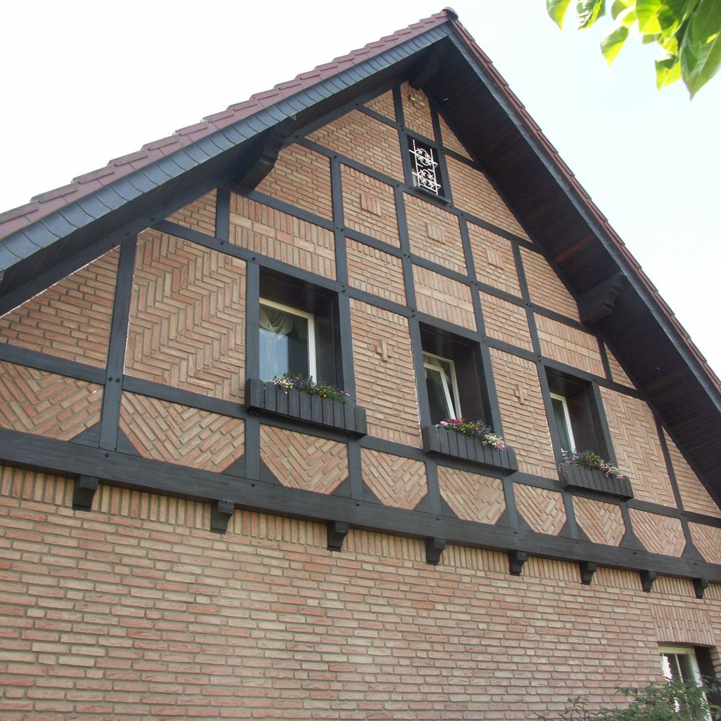 Fachwerkgiebel mit dunkel gestrichenen Balken und Klinker im Fischgrätmuster